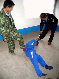 酷刑演示：施暴者将法轮功学员打倒在地，向后反拧双臂，然后用脚猛踩腰部