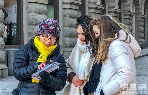 '图5：两位来自德国年轻的姑娘顶着寒风很专注地在听学员讲真相。签名让她们感到很荣幸，她们认为“迫害很可怕，但沉默比迫害更恐怖！”'
